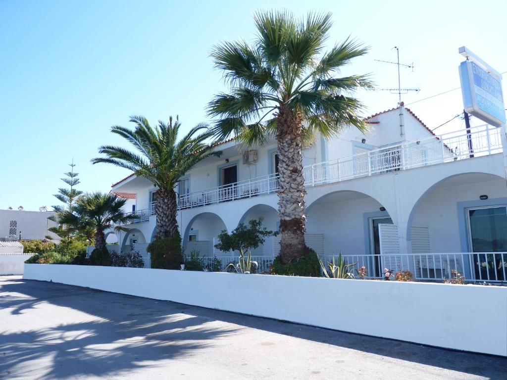 a white building with palm trees in front of it at Manthos in Kalloni