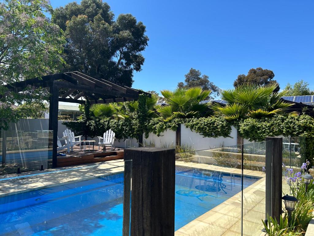 a swimming pool with a patio and an umbrella at Happy Wanderer Motel Bendigo CHILDREN NOT PERMITTED over 18s only in Bendigo