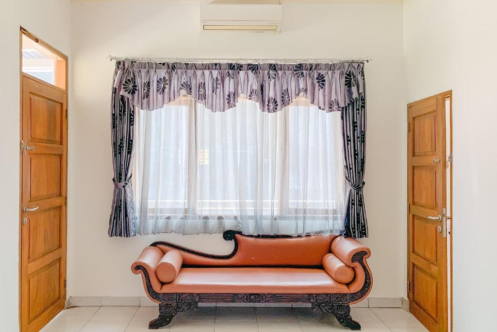 a couch sitting in front of a window at RedDoorz Syariah at Kadungora Garut in Kadungora
