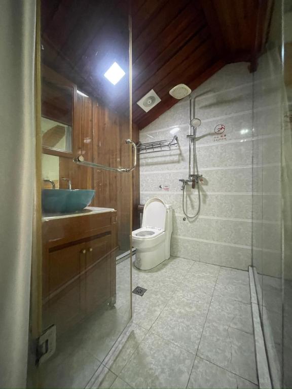 a bathroom with a shower and a toilet and a sink at Bian Cheng Xing Zi Inn in Fenghuang County