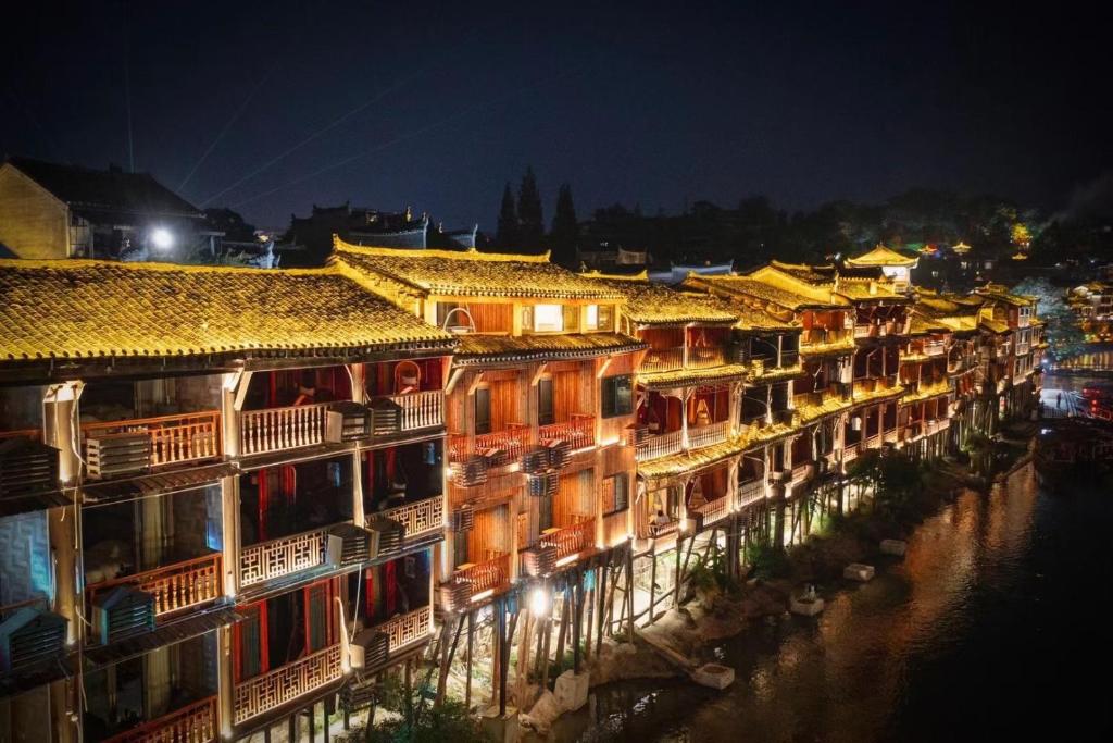 a row of buildings next to a river at night at Bian Cheng Xing Zi Inn in Fenghuang County
