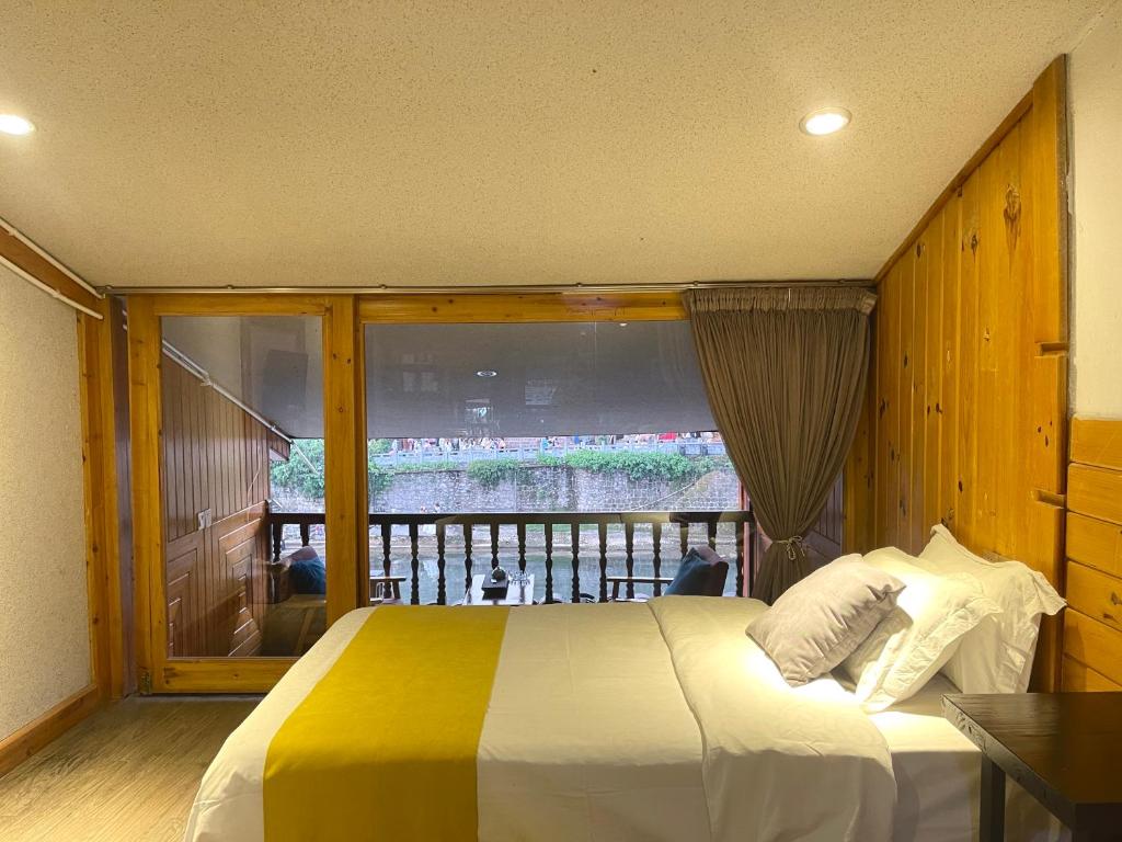 a bedroom with a bed and a large window at Bian Cheng Xing Zi Inn in Fenghuang County