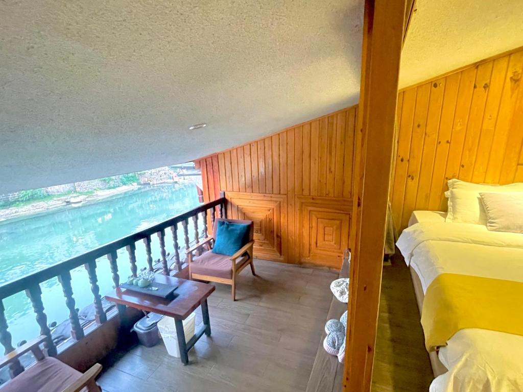 a room with a balcony with a bed and a chair at Bian Cheng Xing Zi Inn in Fenghuang County