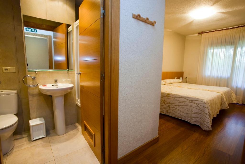 y baño con cama, lavabo y aseo. en Hostal Abodi, en Pamplona