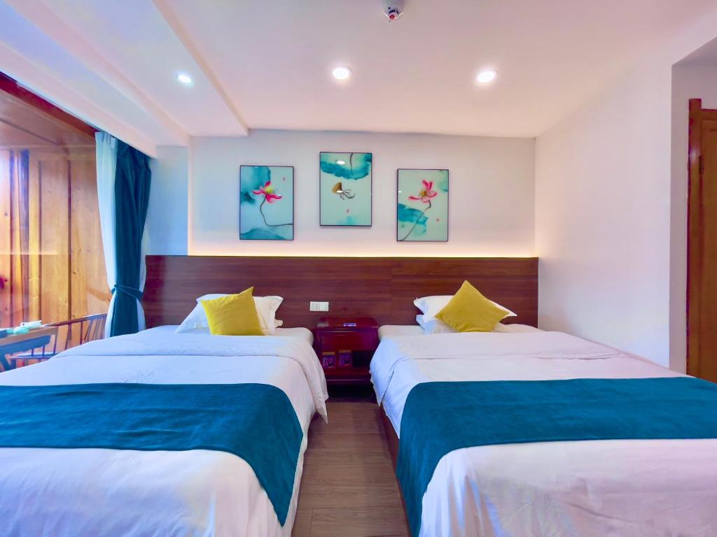 two beds in a room with blue and white at Bian Cheng Xing Zi Inn in Fenghuang County