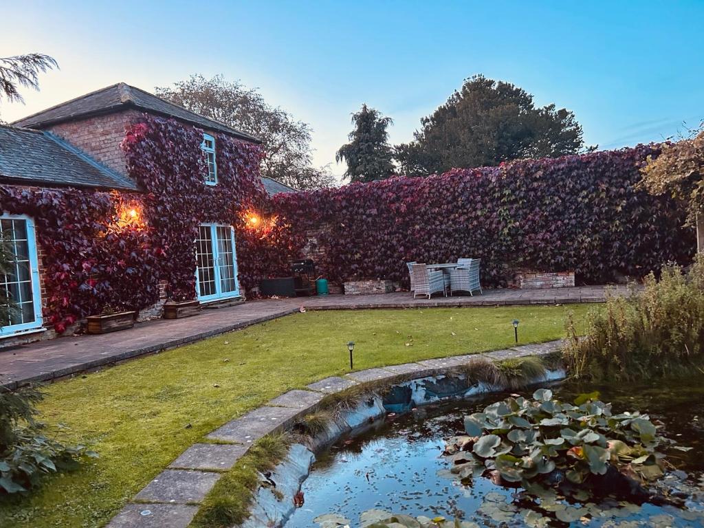 a house covered in ivy with a pond in the yard at The Old Coach House at Stewton in Louth