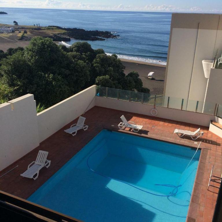 a swimming pool on top of a building with a view of the ocean at Populo Beach Apartment in São Roque