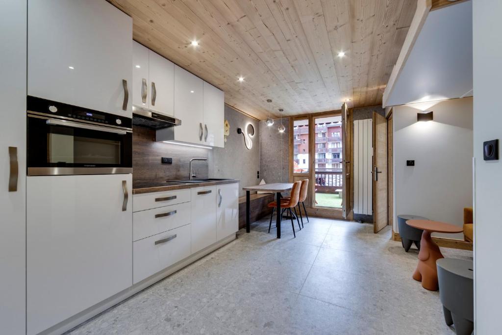 a kitchen with white cabinets and a table with chairs at Appartement Ski aux Pieds 2100m - Le Nid Tignes Val Claret in Tignes