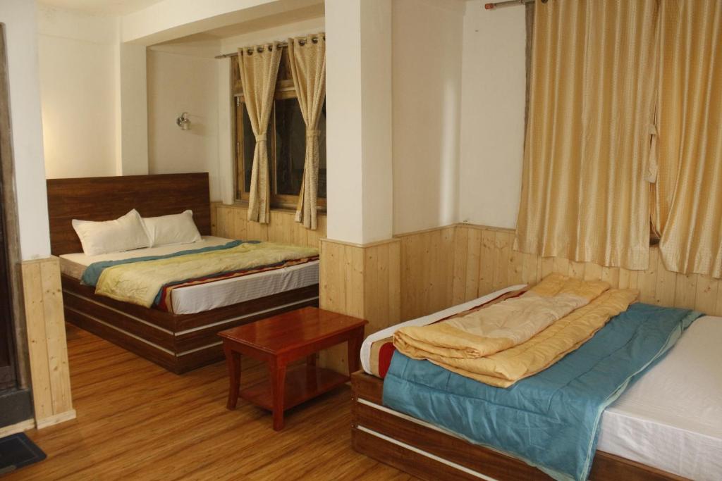 a bedroom with two beds and a table in it at Priyatam Stays in Darjeeling
