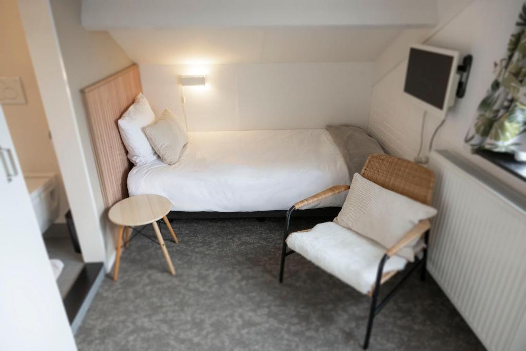 una piccola stanza con un letto e una sedia di B&B De Dream a Leeuwarden
