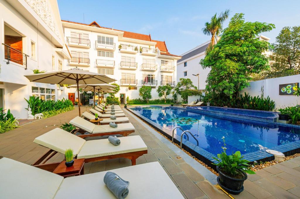 a hotel with a pool and lounge chairs and a building at Sala Siem Reap Hotel in Siem Reap