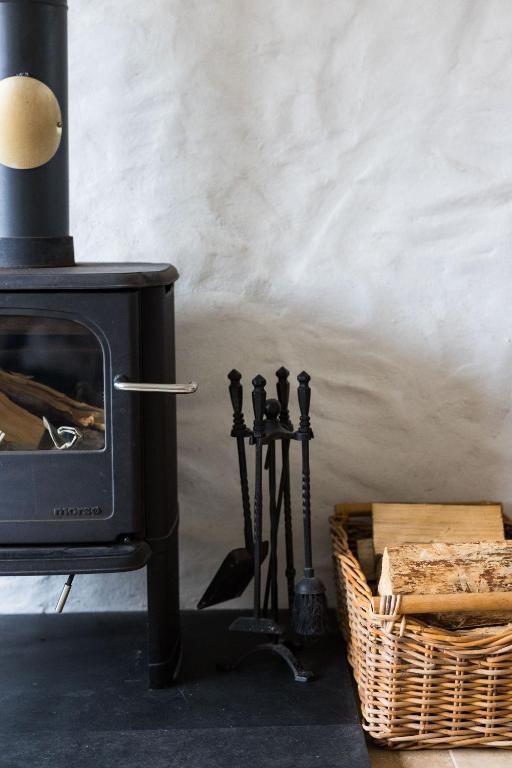a black stove in a room with a basket at The Workshop- Eco Cottage by the Coastal Path in Goodwick