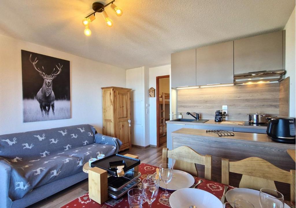 a living room with a blue couch and a kitchen at Le Flocon de Thollon in Thollon