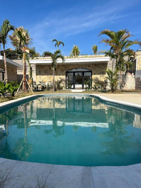 a swimming pool in front of a house at Palacio Balangan Villa in Uluwatu
