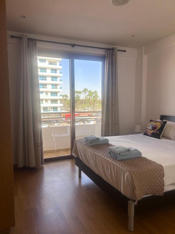 ein Schlafzimmer mit einem Bett und einem großen Fenster in der Unterkunft Ithaki Phinikoudes Apartment No. 205 in Larnaka