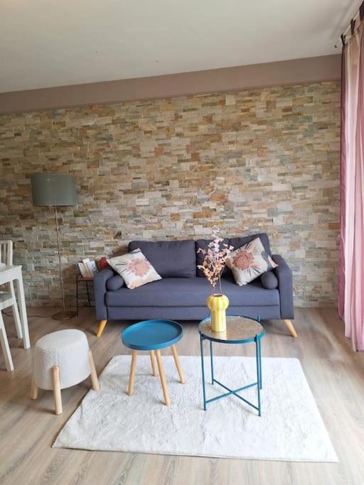 - un salon avec un canapé bleu et un mur en briques dans l'établissement T4 rennais -Métro & Rocade, à Rennes