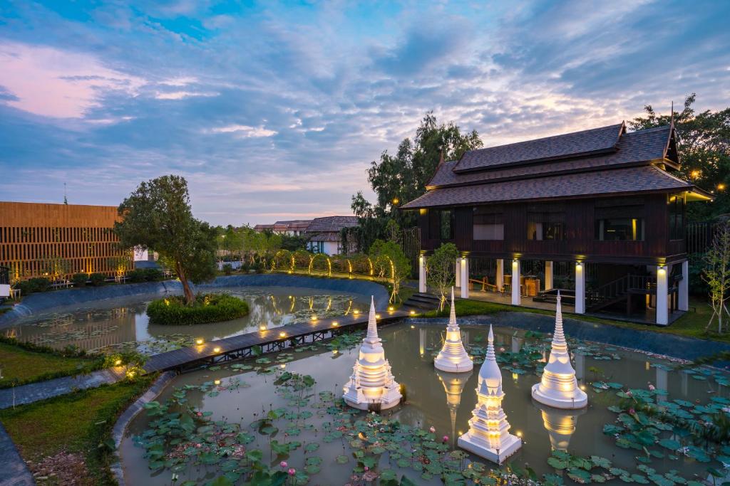 a building with a pond with flowers in front of it at THANN Wellness Destination in Phra Nakhon Si Ayutthaya