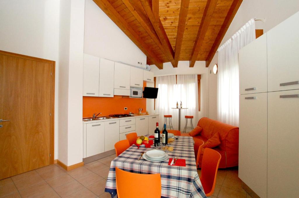 a kitchen and dining room with a table and orange chairs at Residence Roberta in Caorle