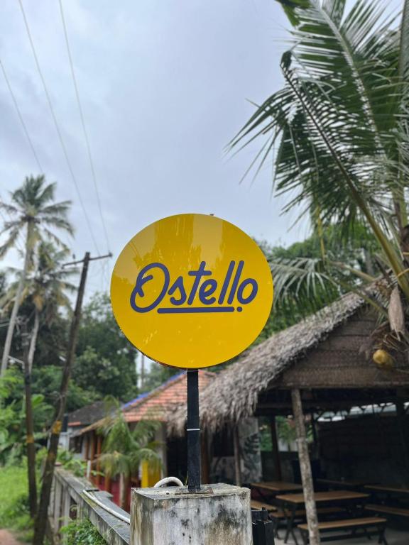 a yellow sign on a pole in front of a building at Ostello in Varkala