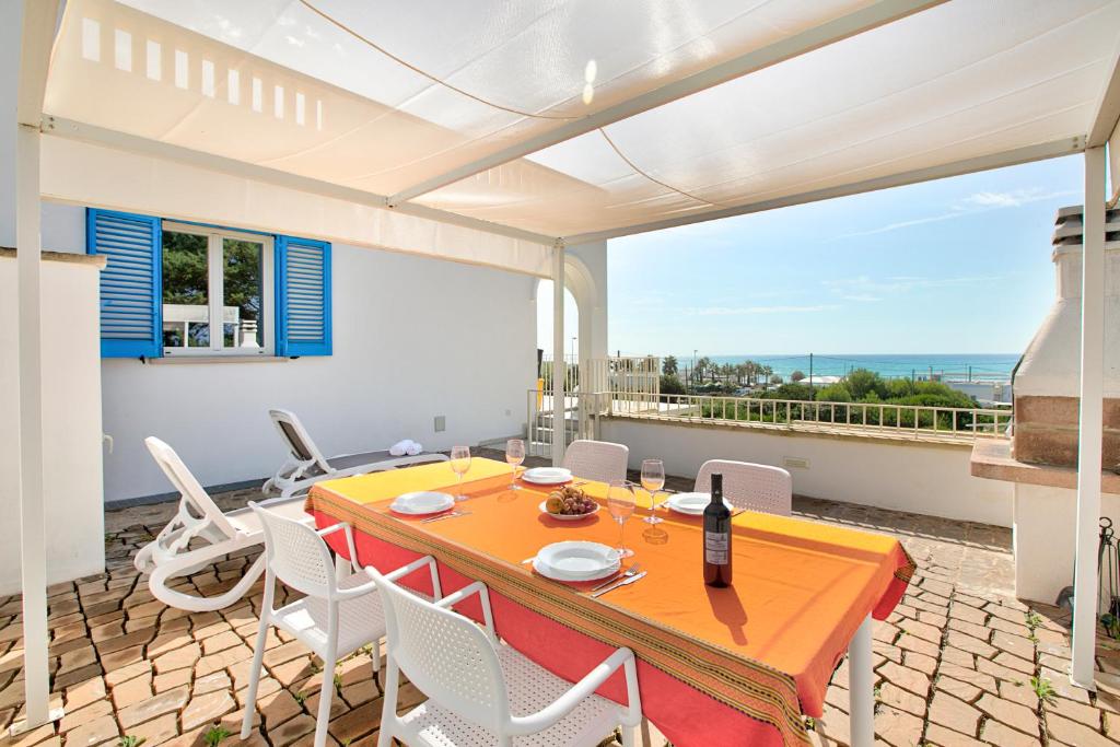 a dining room with a table and chairs on a balcony at La Primula Apartments in Salve