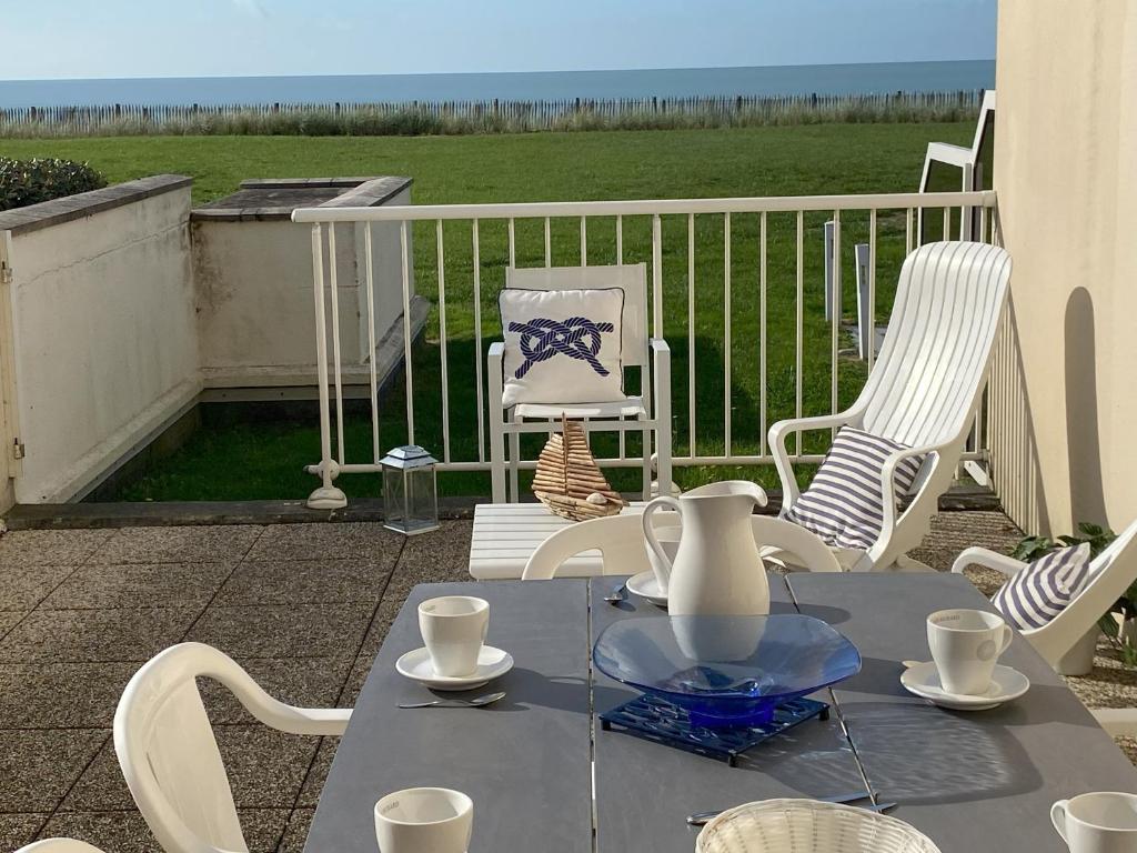 - une table et des chaises sur une terrasse avec vue sur un champ dans l'établissement Appartement de la mer, à Jullouville