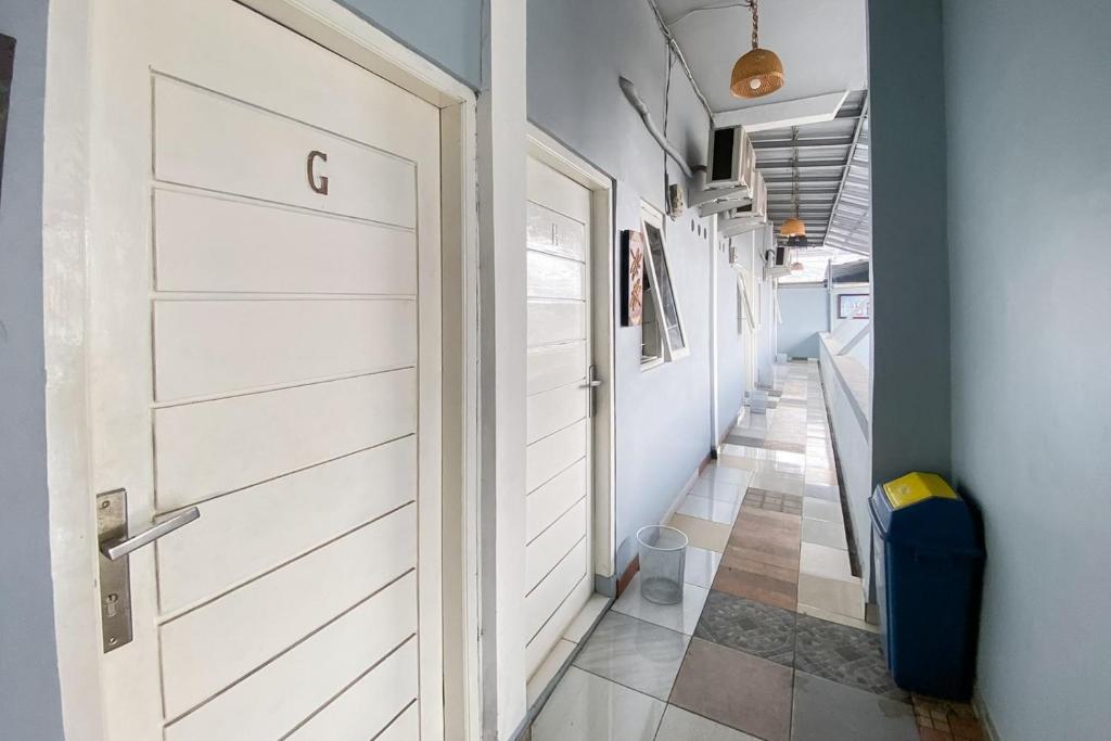 un couloir avec une porte blanche et du carrelage. dans l'établissement Andung Residence Lampung RedPartner, à Bandar Lampung