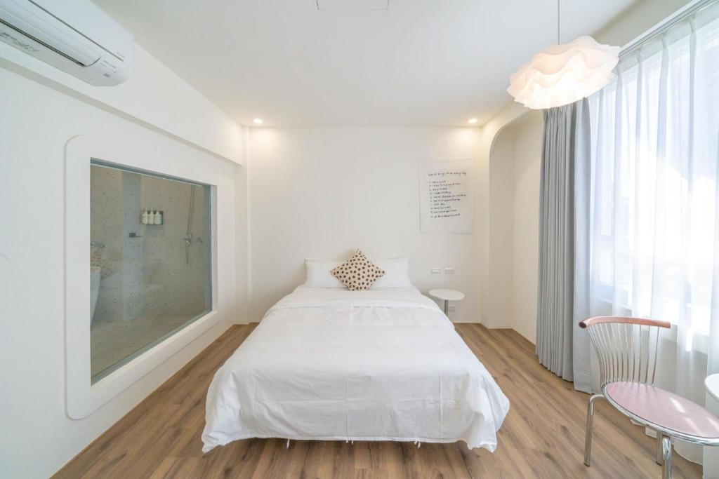 a white bedroom with a bed and a window at Nantuju in Ch'ih-k'an-lou