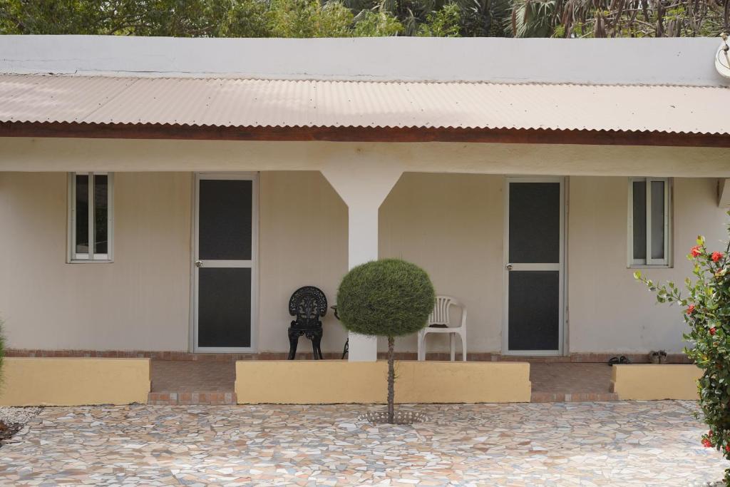 a white house with two chairs and a bush at Dafa Tanga Lodge in Sanyang