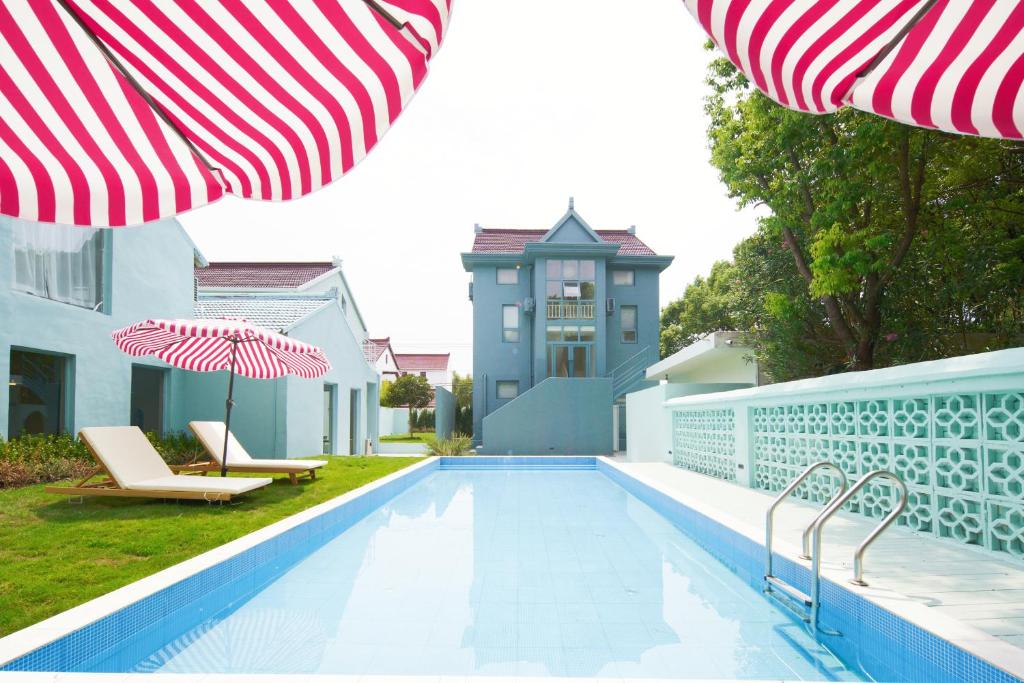 上海市にあるMila Zai Ye Wai Guest House Shanghaiのスイミングプール(パラソル2本、椅子2脚付)、