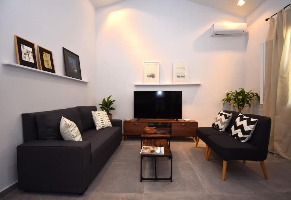 a living room with a black couch and a tv at Casa Campagnolo in Corfu