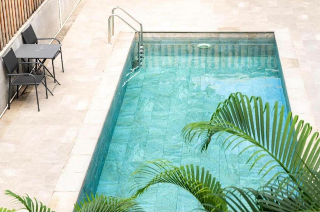 a swimming pool with blue water and palm trees at Point de Mire in Rivière Noire