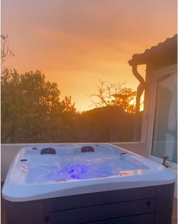 a hot tub with a sunset in the background at L'OASIS BLEUE Spa et Terrasse in Sète