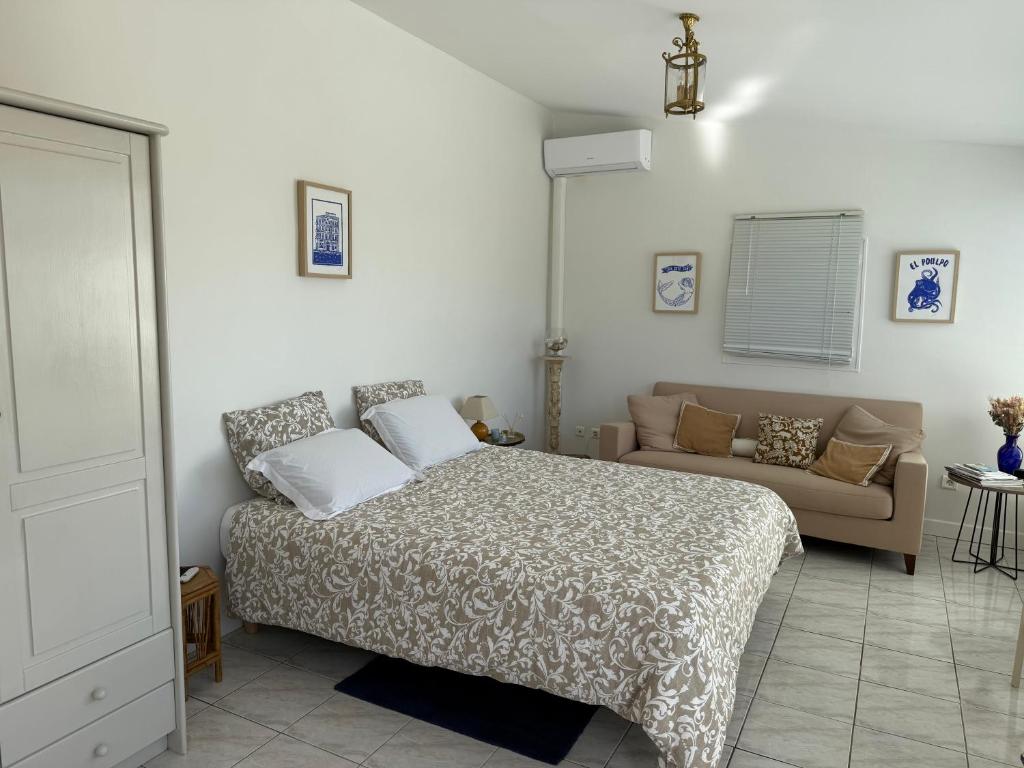 une chambre avec un lit et un canapé dans l'établissement L'OASIS BLEUE spa et terrasse, à Sète