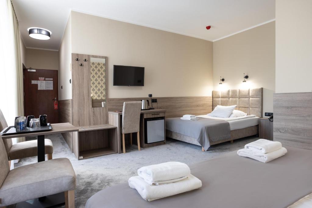 a hotel room with two beds and a television at Hotel Maksymilian in Krakow