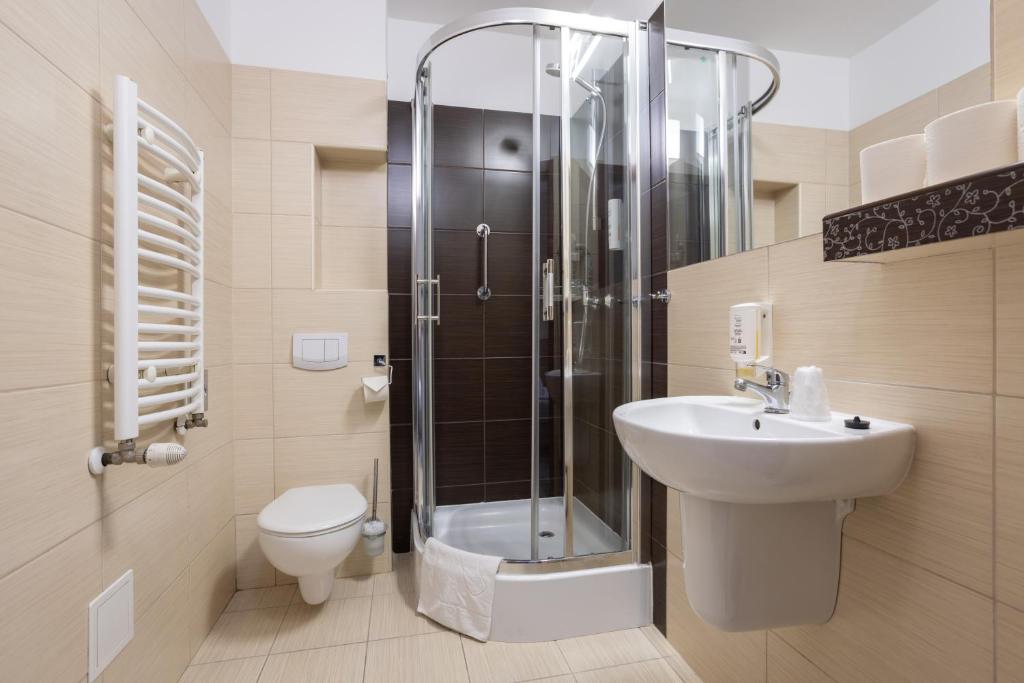 a bathroom with a shower and a sink and a toilet at Hotel Maksymilian in Krakow
