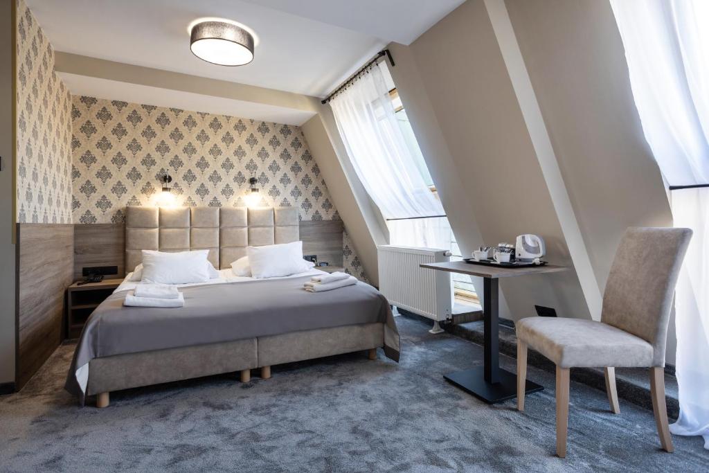 a bedroom with a bed and a desk and a chair at Hotel Maksymilian in Krakow