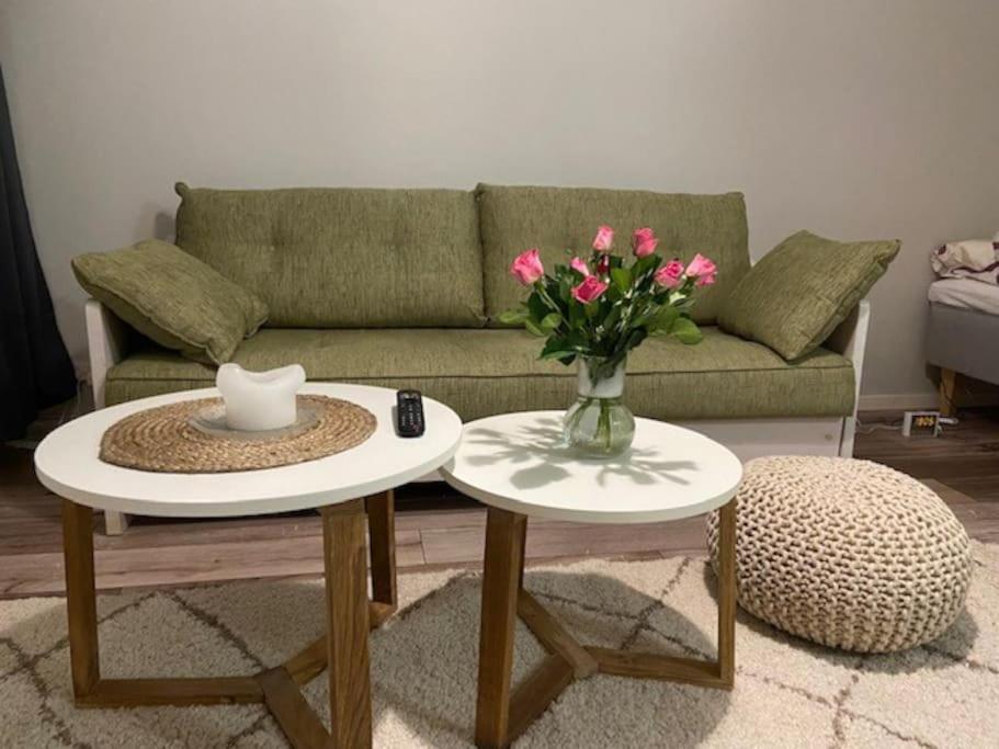 a living room with two tables with a vase of flowers at Käytännöllinen yksiö rauhallisella alueella! in Hyvinkää