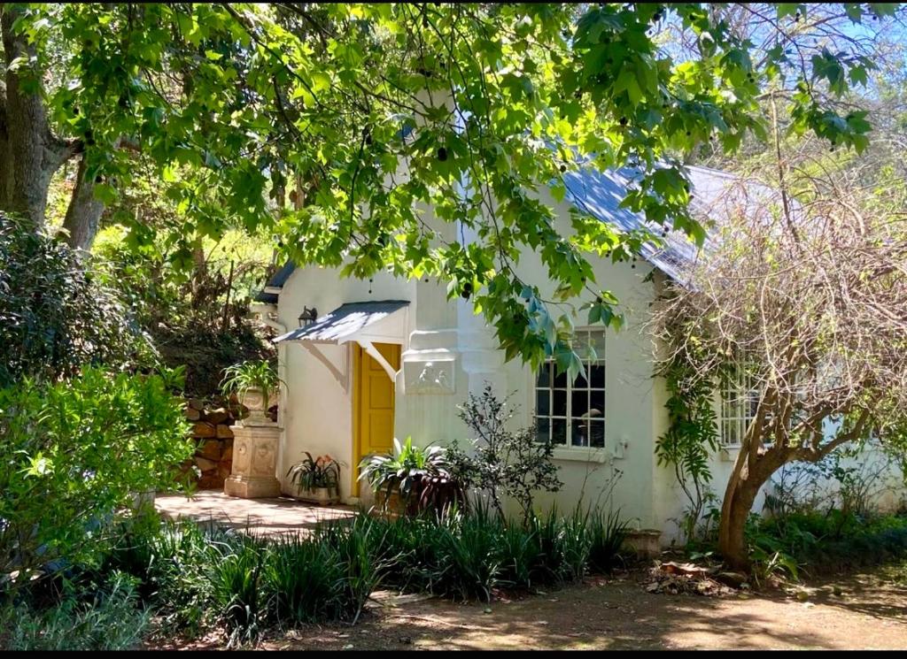 Casa blanca con puerta amarilla y árboles en Yellowwoods Farm - POOL COTTAGE (self-catering), en Curryʼs Post