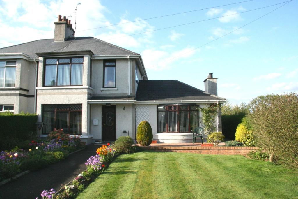 a white house with a yard with flowers at Ken-Mar House Bed and Breakfast in Ballymoney