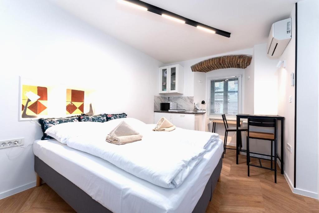 a bedroom with a large white bed and a kitchen at Corso Apartments in Rijeka