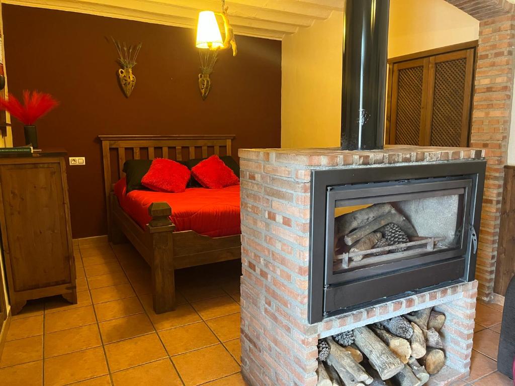 a living room with a fireplace with a bed in the background at La Casita Roja Del Arcoíris in Riópar