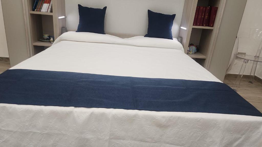 Una cama blanca y azul con almohadas azules. en Pomona Guest House, en Salerno