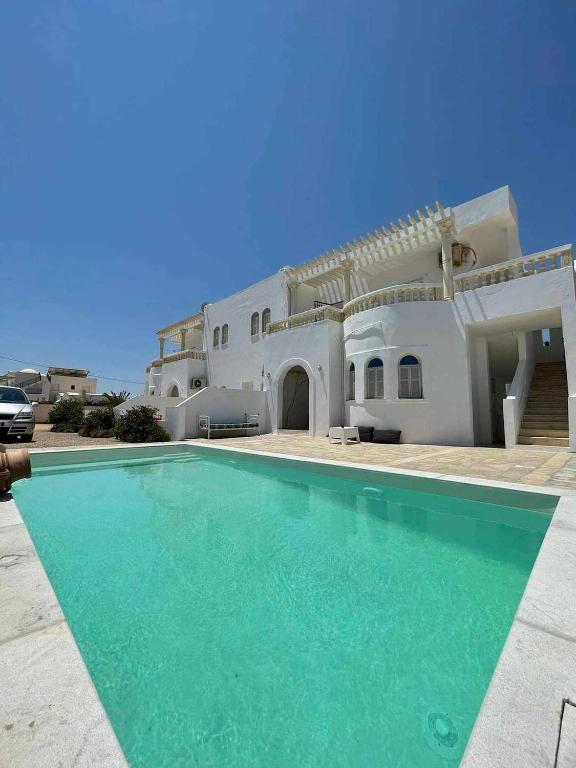 a house with a swimming pool in front of it at Résidence SUN SHINE DJERBA in Midoun