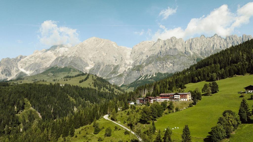 eine Bergkette mit einem Haus auf einem grünen Feld in der Unterkunft Hotel Bergheimat in Mühlbach am Hochkönig