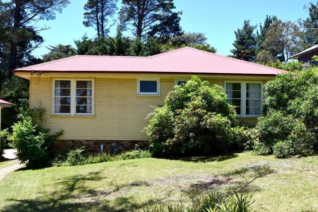a small yellow house with a pink roof at Blackheath Holiday Cabins in Blackheath