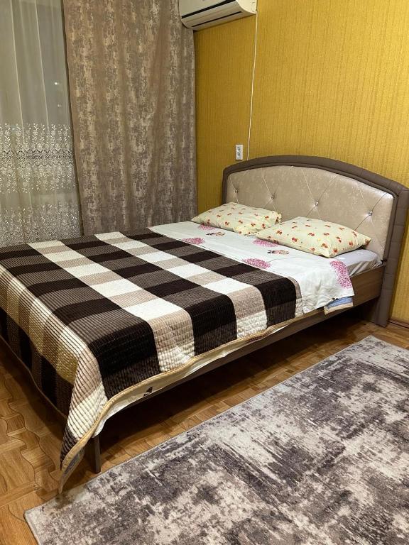 a bed with a black and white comforter in a room at Economy - class apartment in Pavlodar