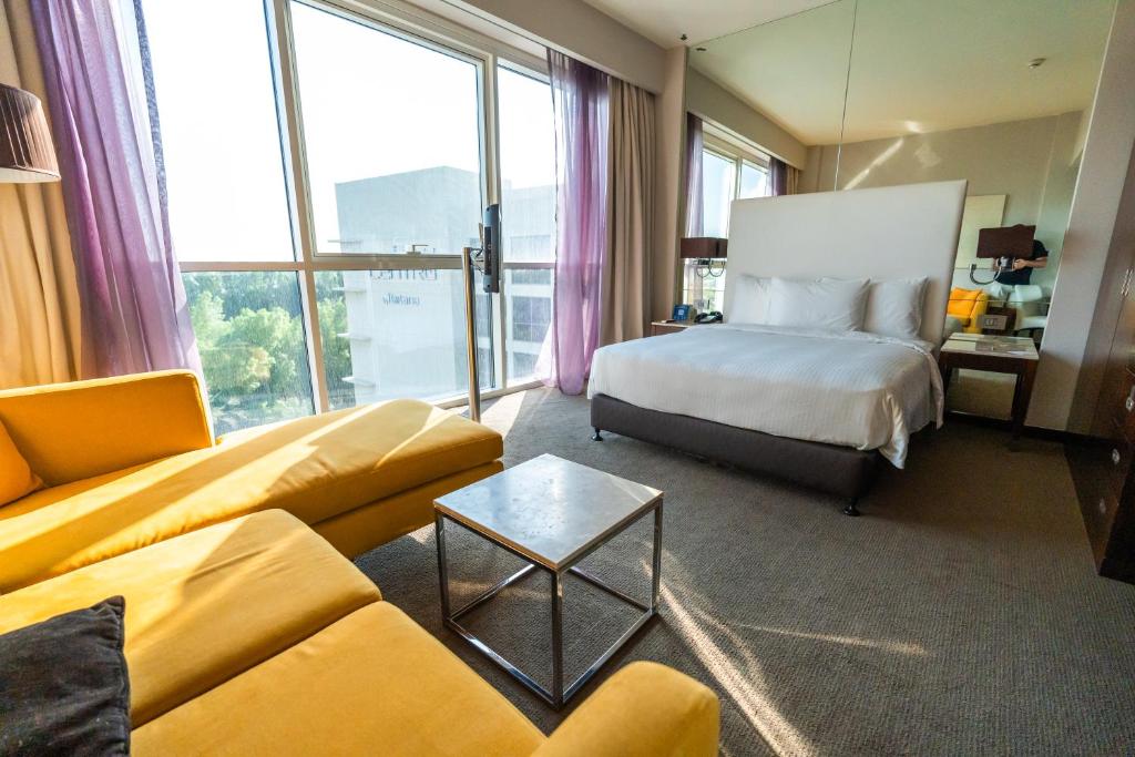a hotel room with a bed and a couch at Centro Sharjah in Sharjah