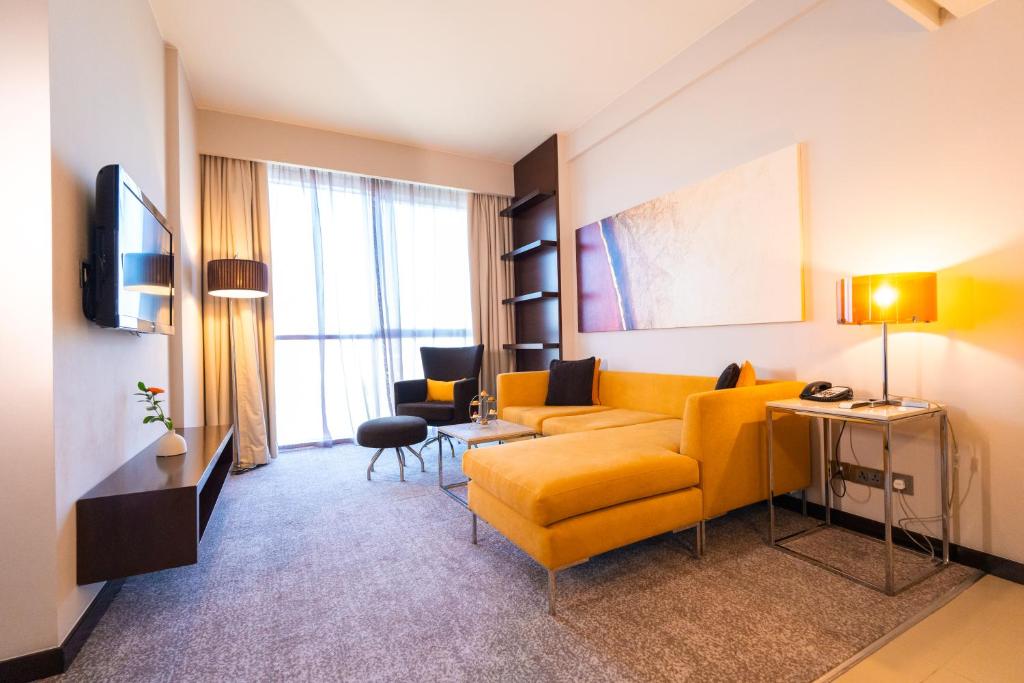 a living room with a yellow couch and a tv at Centro Sharjah in Sharjah