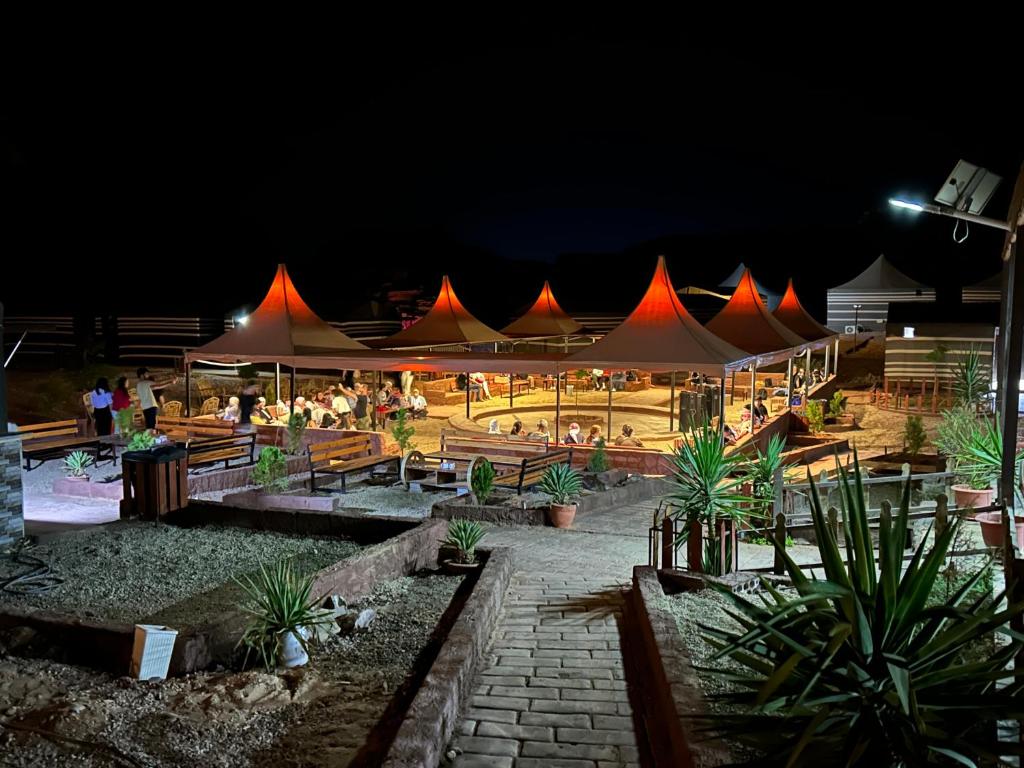 a group of tents with people sitting under them at night at Desert Island Camp in Wadi Rum