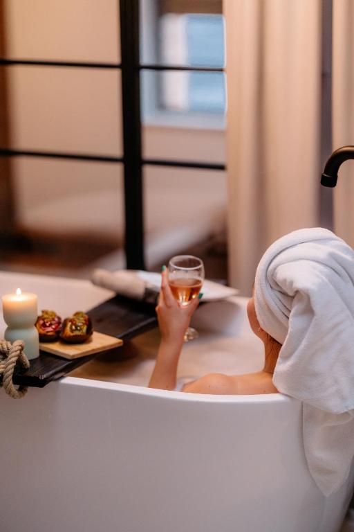 a woman sitting in a bath tub holding a glass of wine at Loft 16 - Luksus & Relax - Wanna, Netflix, Parking in Iława